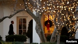 A Christmas wreath hangs on the door to the Oval Office as President Barack Obama returns to the White House in Washington, December 15, 2014.