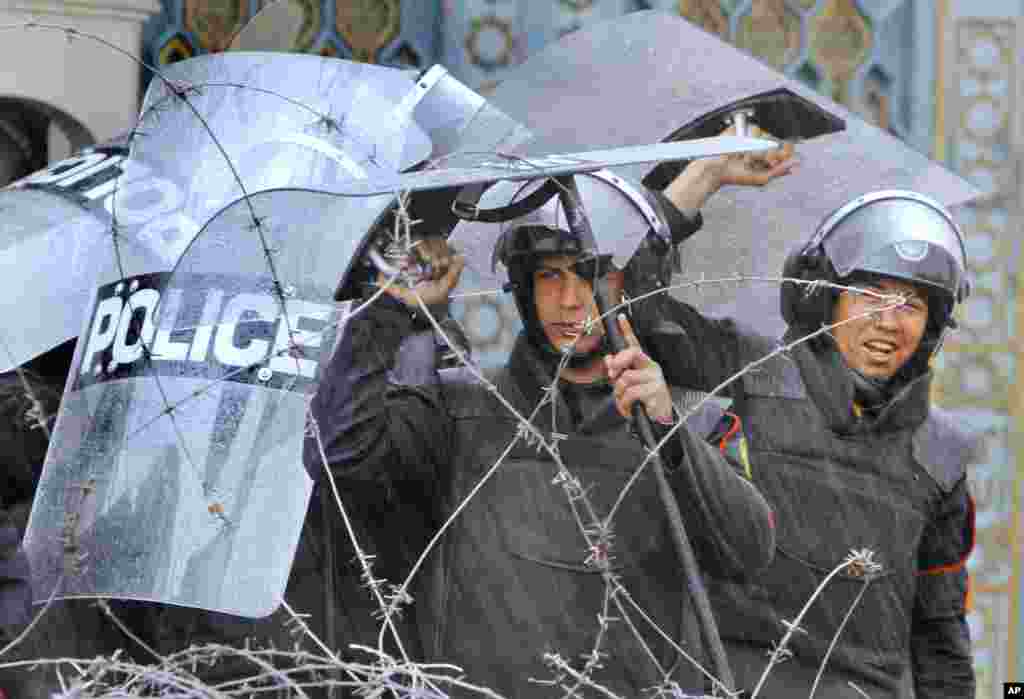 Egyptian security forces protect themselves from heavy rains in front of the presidential palace in Cairo, Egypt, Feb. 1, 2013.