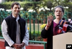 India's ruling Congress party president Sonia Gandhi, right addresses the media as Vice President Rahul Gandhi smiles in New Delhi, Dec. 8, 2013.