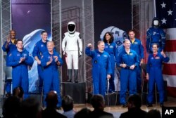 De izquierda a derecha los astronautas Victor Glover, Robert Behnken, Michael Hopkins, Douglas Hurley, Eric Boe, Sunita Williams, Christopher Ferguson, Josh Cassada y Nicole Mann son presentados en un evento de la NASA para anunciar que volarán al espacio en una cápsula SpaceX Dragon.