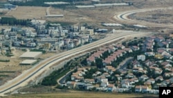 FILE - An aerial view over West Bank showing a Palestinian village, left, and a Jewish settlement, right, separated by a wall, part of the separation fence Israel is building.