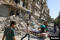 FILE - People remove belongings from a damaged site after an air strike Sunday in the rebel-held besieged al-Qaterji neighbourhood of Aleppo, Syria, Oct. 17, 2016.