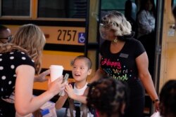 Para guru SD Tussahaw di McDonough, Georgia, menyambut siswa mereka yang turun dari bus sekolah, Rabu, 4 Agustus 2021. (AP)