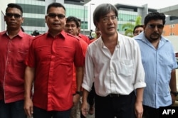 FILE - This picture taken on November 3, 2016 shows Jamal Yunos (2nd L), a division head member of the ruling United Malays National Organisation (UMNO) party, walking with Malaysiakini's editor-in-chief Steven Gan (2nd R) before their press conference in Petali