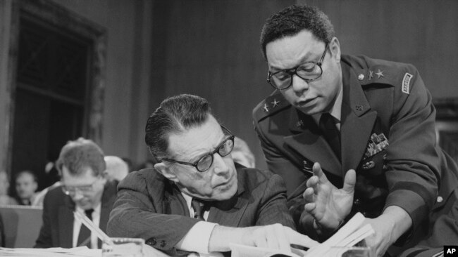 FILE - In this Feb. 8, 1985 photo, US Defense Secretary Casper Weinberger confers with Army Maj. Gen. Colin Powell during testimony before the Senate Budget Committee on Capitol Hill in Washington.