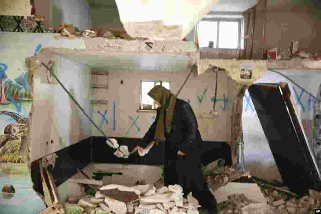 Seorang perempuan Palestina memeriksa rumah Ehab Maswada yang dihancurkan oleh militer Israel di Hebron, Tepi Barat.