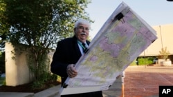Russ Tidwell, a former lobbyist who is helping minority rights groups sue Texas over Republican-drawn voting maps holds a set of maps as he makes his way to the federal court house, July 10, 2017.
