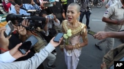 Theary Seng, a Cambodian-American lawyer, dressed in a traditional Khmer Apsara dance costume, speaks to media as she arrives to continue her trial in the municipal court in Phnom Penh, Cambodia, Tuesday, Dec. 7, 2021. (AP Photo/Heng Sinith) 