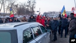 Protesters chant slogans while blocking a main road leading into the Moldovan capital during a protest in Chisinau, Moldova, Jan. 24, 2016.