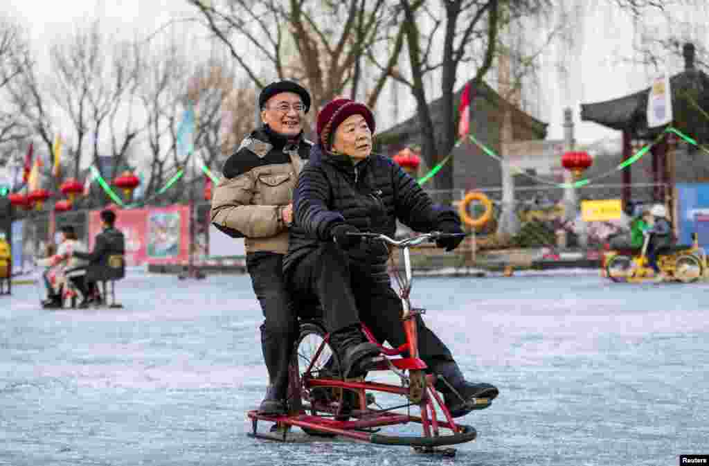 A couple rides a skating bicycle on the frozen Houhai Lake in central Beijing, China.