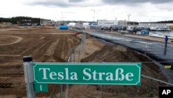 Tanda jalan 'Tesla Street 1' terlihat di depan lokasi konstruksi pabrik mobil listrik Tesla di Gruenheide dekat Berlin, Jerman, 2 September 2020. (AP Photo/Michael Sohn)