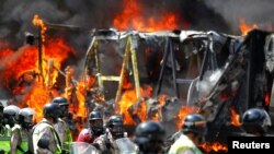 Riot security forces congregate next to a government truck that was set on fire during a rally against Venezuelan President Nicolas Maduro's government in Caracas, Venezuela, June 22, 2017.