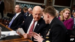 Director of National Intelligence James Clapper, center, talks with National Security Agency and Cyber Command chief Adm. Michael Rogers, on Capitol Hill in Washington, Jan. 5, 2017.