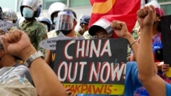 FILE - Protesters hold slogans during a rally in front of the Chinese Consulate in Makati city, Philippines, July 12, 2021. Chinese coast guard ships blocked and used water cannons on two Philippine supply boats heading to a disputed shoal occupied by Fil