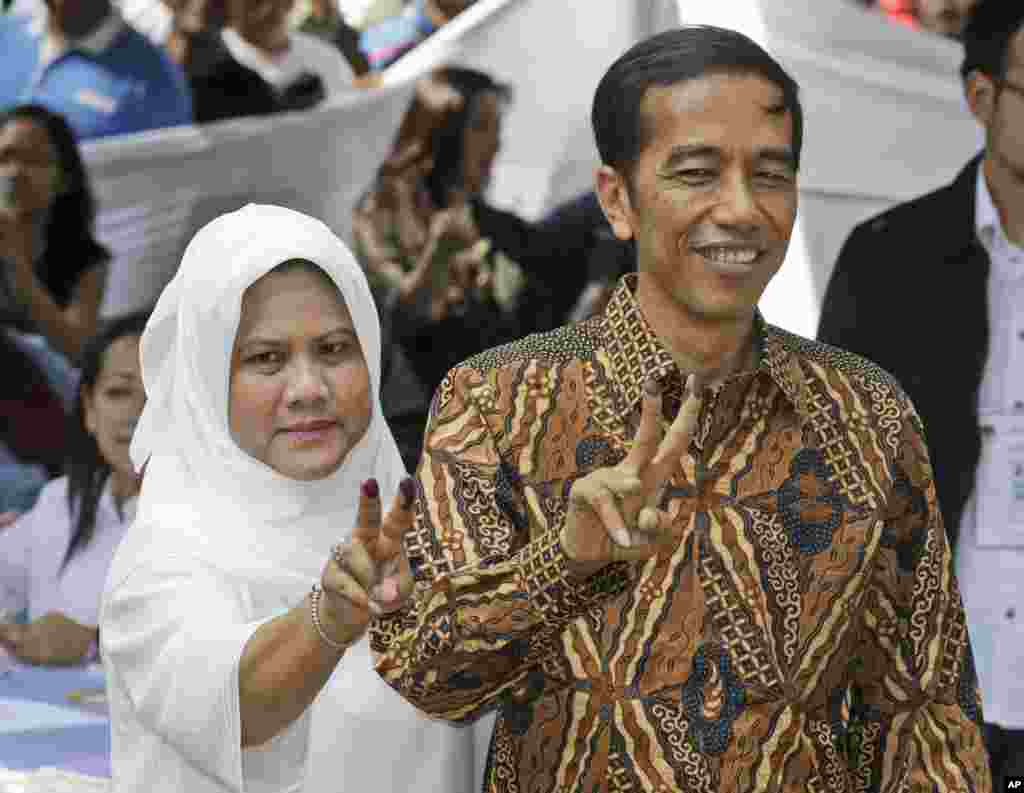 Indonesian presidential candidate Joko Widodo, popularly known as "Jokowi," and his wife Iriana, show their inked fingers after casting their ballots during the presidential election in Jakarta, July 9, 2014.