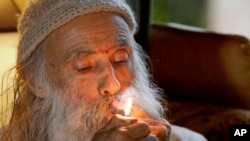 FILE - In this Thursday, Oct. 13, 2016 photo, Swami Chaitanya lights a "grower's joint" marijuana cigarette at his home near Laytonville, California.