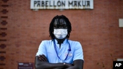 Mbaye Babacar Diouf stands for a photo wearing his nurse's clothing, at Basurto hospital, in Bilbao, northern Spain, Wednesday, Nov. 18, 2020.