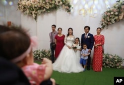 La mariée Thanh Mai et le marié Duc Trung posent pour une photo avec leurs proches lors de leur mariage à Hanoi, au Vietnam, le dimanche 28 juin 2020. Le couple a célébré son mariage, qui a été reporté en mars en raison du verrouillage social, alors que le Vietnam se détend. À la normale.