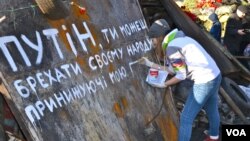 The girl is painting a slogan that reads "Putin you can kill us but you can't take away our freedom" in Kyiv's Independence Square, Ukraine, Mar. 8, 2014. (Jamie Dettmer/VOA)