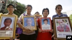 Relatives of the victims hold portraits of their loved ones during a commemorate session of a rally at Ratchaprasong Intersection in Bangkok, Thailand, May 19, 2012.