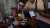 Warga Myanmar berkumpul untuk minum di sebuah kedai teh di Yangon sambil membuka laman Facebook dengan ponsel mereka. (Foto: AFP)