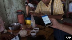 Warga Myanmar berkumpul untuk minum di sebuah kedai teh di Yangon sambil membuka laman Facebook dengan ponsel mereka. (Foto: AFP)