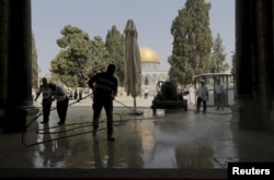 Palestinians clean the Al Aqsa mosque after clashes between Israeli police and Palestinians on the compound known to Muslims as Noble Sanctuary and to Jews as Temple Mount in Jerusalem's Old City, Sept. 15, 2015.