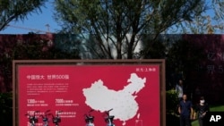 People walk by a map showing Evergrande development projects in China at an Evergrande new housing development in Beijing, Sept. 22, 2021.