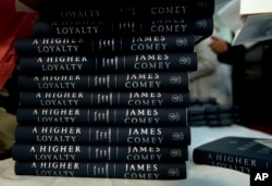 Politics and Prose bookstore staff members hands out former FBI director James Comey's book during a stop on his book tour for "A Higher Loyalty," April 30, 2018, in Washington.