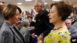 Democratic presidential candidate Sen. Amy Klobuchar, center, talks with State Rep. Heather Matson, right, at the Ankeny Area Democrats' Winter Banquet, Feb. 21, 2019, in Des Moines, Iowa.