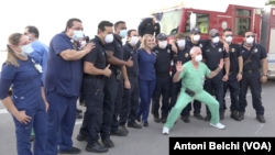 Miembros del personal sanitario del hospital Mount Sinai de Miami Beach se toman fotografías con los bomberos de la ciudad, que fueron hasta las instalaciones hospitalarias para rendir tributo al trabajo que están haciendo frente a la pandemia.