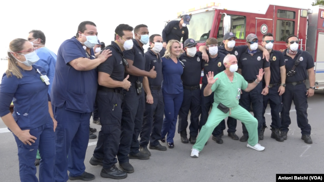 Miembros del personal sanitario del hospital Mount Sinai de Miami Beach se toman fotografías con los bomberos de la ciudad, que fueron hasta las instalaciones hospitalarias para rendir tributo al trabajo que están haciendo frente a la pandemia.