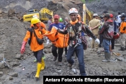 FILE - Rescue team members carry the body of a miner after a landslide hit Srumbung Village in Magelang, Indonesia, Dec. 18, 2017.