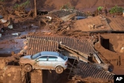 A car and two dogs are seen on the roof of destroyed houses at the small town of Bento Rodrigues after a dam burst on Thursday in Minas Gerais state, Brazil, Nov. 6, 2015.