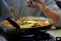 FILE - Budae jjigae, or "army stew," simmers as it sits atop a heating plate at a Korean restaurant in Shoreline, Washington, Dec. 12, 2017.