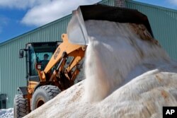 David Osgood, crew leader of the public works department, mixes road salt, March 12, 2018, in Freeport, Maine.