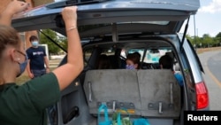 Laura Brooks' daughter Scarlett looks back as free groceries are loaded in their minivan at the monthly Weymouth Market in South Weymouth, Massachusetts, U.S., August 5, 2020. REUTERS/Brian Snyder