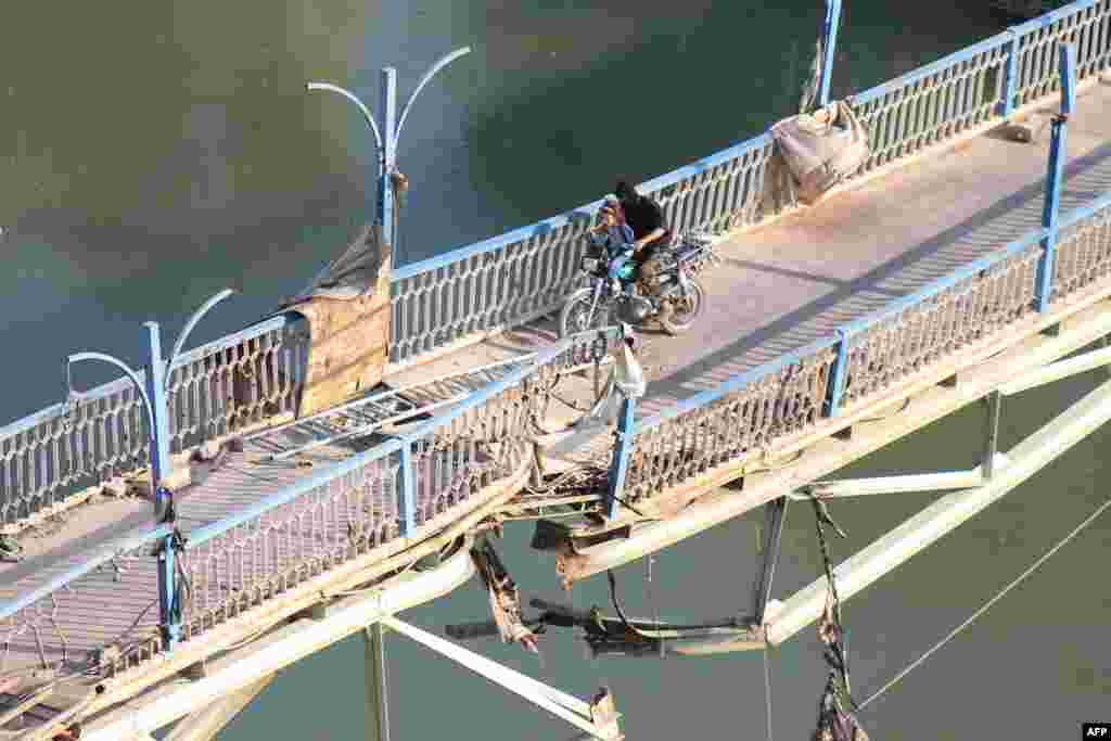 A rebel fighter and a child cross a damaged bridge in Syria&#39;s eastern town of Deir Ezzor.