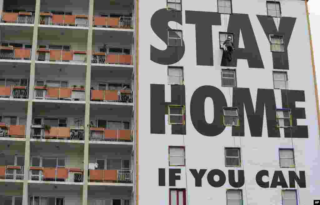 A billboard is put up on an apartment building in Cape Town, South Africa, before the country of 57 million people goes into a national lockdown for 21 days to fight the spread of the new coronavirus.