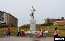 FILE - Pupils of a local nursery school and adults walk past a monument to Soviet state founder Vladimir Lenin in Vorgashor settlement outside the far northern city of Vorkuta, Russia, Sept. 17, 2018.