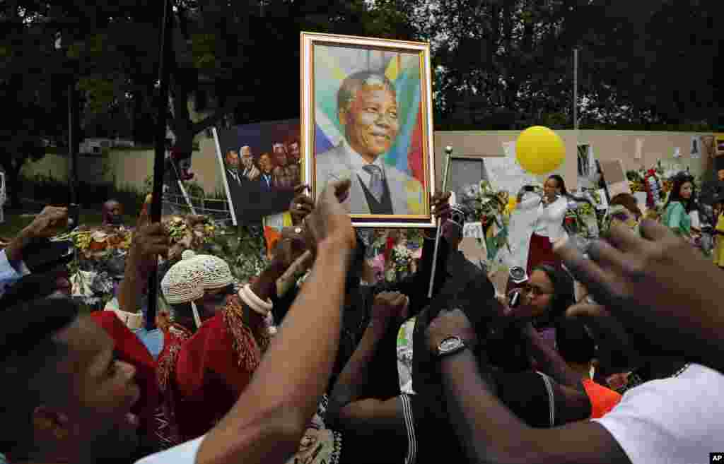 Mourners sing outside the home of Nelson Mandela in Johannesburg, Dec. 9, 2013.