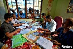 FILE - People wait to check their names on the draft list at the National Register of Citizens (NRC) centre at a village in Nagaon district, Assam state, India, July 30, 2018.