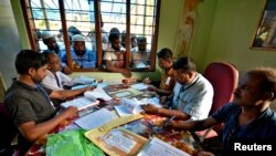 FILE - People wait to check their names on the draft list at the National Register of Citizens (NRC) centre at a village in Nagaon district, Assam state, India, July 30, 2018. 