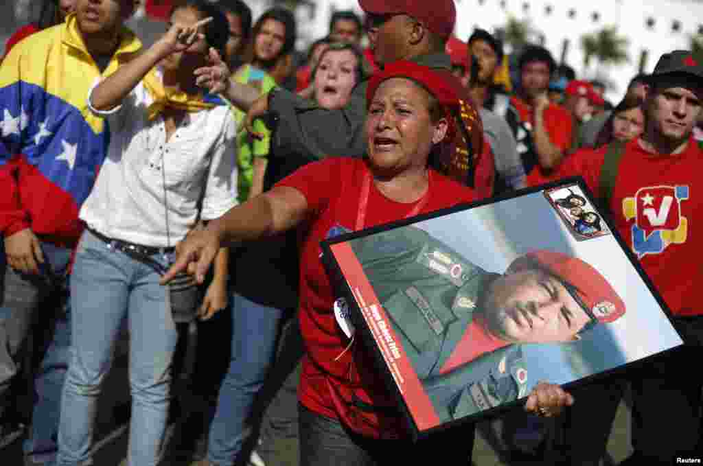 Supporters of Venezuela's late President Hugo Chavez protest over others cutting the line as they wait to view his body in state at the Military Academy in Caracas, March 7, 2013. 