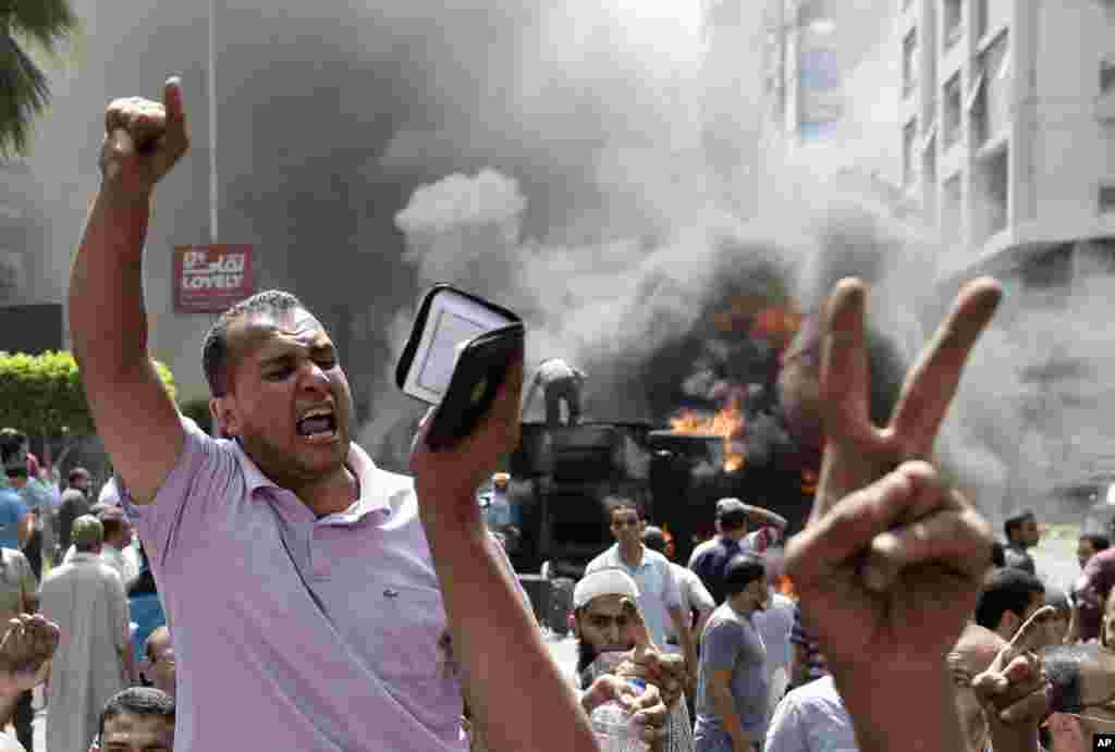 Para pendukung presiden terguling Mohamed Morsi meneriakkan slogan-slogan melawan Menteri Pertahanan Mesir Jenderal Abdel-Fattah el-Sissi dalam bentrokan dengan pasukan keamanan di Mohandessin, Kairo (14/8). (AP/Hassan Ammar)