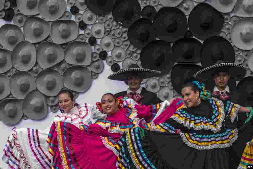 Mexican regional dancers perform in front of a mosaic made with Mexican traditional hats, during a Guinness record ceremony for the world's largest mosaic made with hats, in Guadalajara. The mosaic was made with more than 1,000 hats and measures 10 meters high.