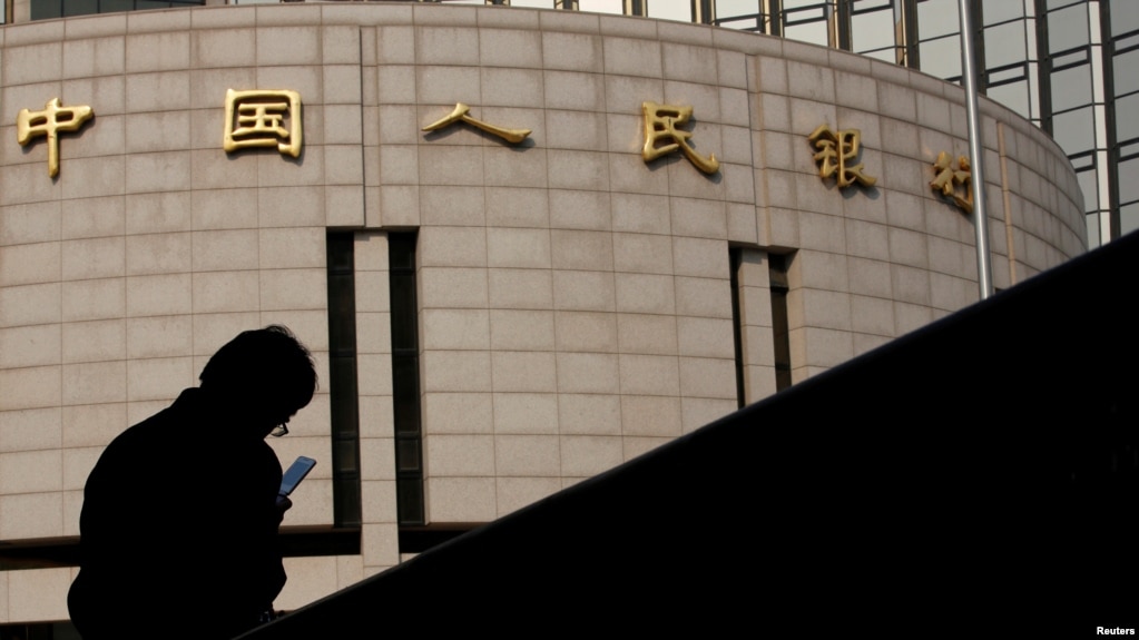 资料照：一名男子坐在中国人民银行总部大楼外。(photo:VOA)