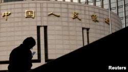 资料照：一名男子坐在中国人民银行总部大楼外。（路透社2013年10月17日）