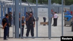Security guards stand by the gate of the transit zone where migrants are hosted in container camps and their asylum claims are processed, in Tompa, Hungary, June 14, 2017.