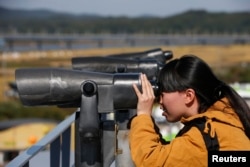 FILE - A Chinese tourist looks towards the north through a pair of binoculars at the Imjingak pavilion near the demilitarized zone which separates the two Koreas, in Paju, north of Seoul, Oct. 16, 2013.